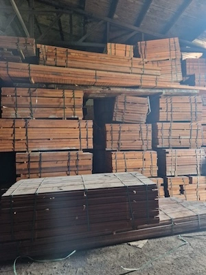 Bundles of stacked timber planks secured with strapping inside a dimly lit warehouse with wooden beams