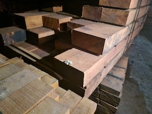 Close-up view of stacked hardwood timber beams in a warehouse, showing grain texture and cut edges